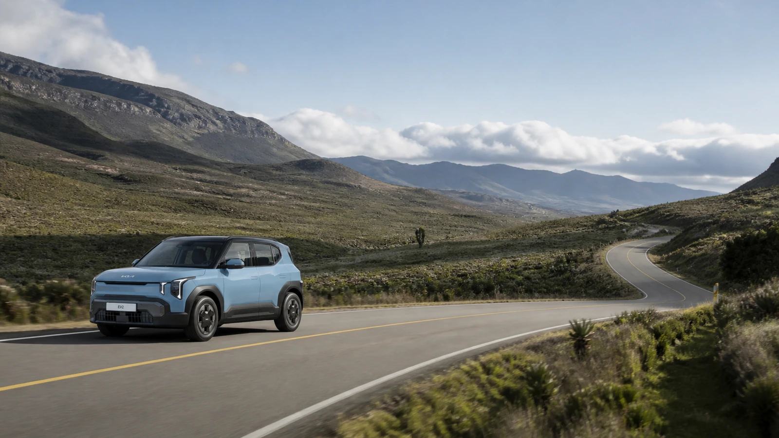 Kia EV2 azul en una carretera curva entre montañas andinas